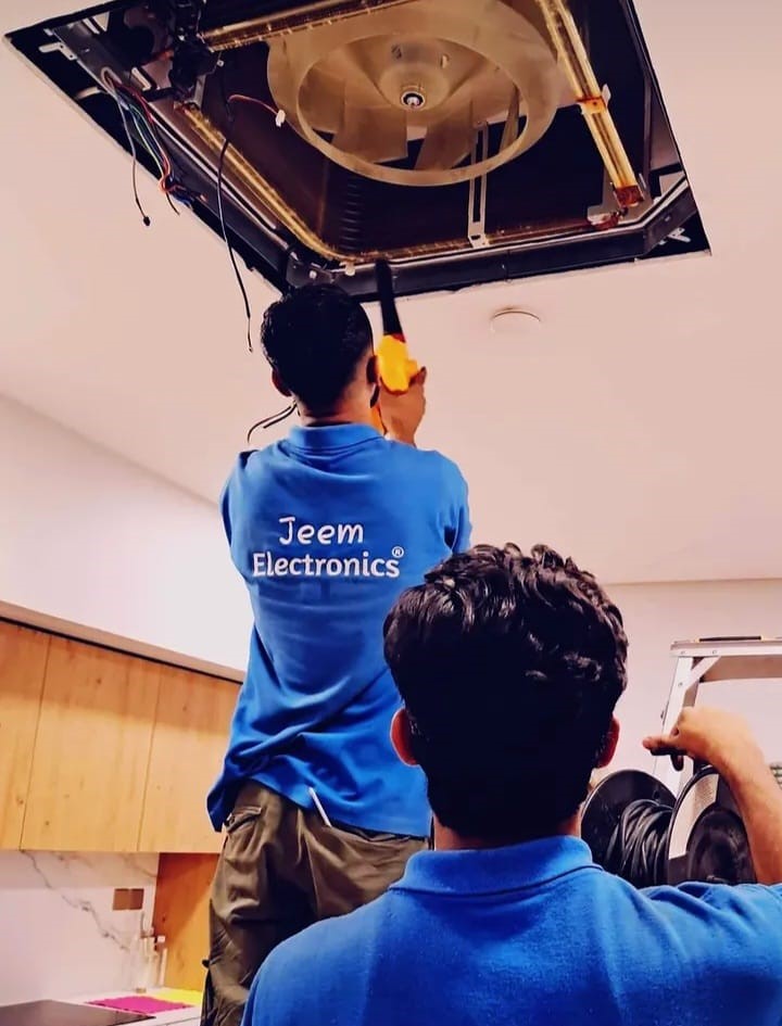 Jeem Electronics technician repairing a ceiling AC unit